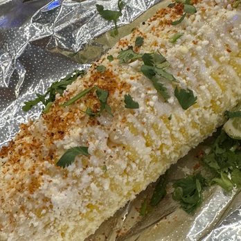 Lupe's 55 Cantina - Pollo burrito - A baked dish, possibly a casserole or stuffed bread, is covered with a breadcrumb topping and garnished with fresh green herbs. It is placed on crinkled aluminum foil, with some herbs scattered around. The dish appears to have a golden-brown crust and is presented in a casual setting. - Mexican Near Me - Hampton, New Hampshire
