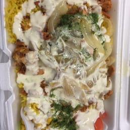 Chicken over rice with grilled onions corn and tomatoes. White sauce and green cilantro sauce. Chicken over rice with grilled onions corn and tomatoes. White sauce and green cilantro sauce.