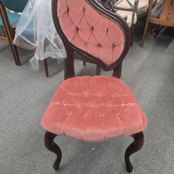 Leo's Upholstery - Antique chair before - A pink velvet upholstered chair with tufted cushioning and a dark wooden frame, featuring carved floral details on the backrest. - Furniture Reupholstery Near Me - Chicago, Illinois