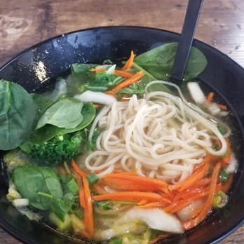 Fun Noodle Bar - A bowl of noodle soup with fresh vegetables like carrots, spinach, broccoli, and cabbage, served on a wooden table. - Chinese Near Me - Santa Fe, New Mexico