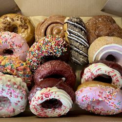 Rocco's Doughnut Company - Box of Happiness Feb 2026 including Maple Bacon, Strawberry Sprinkles, Fruity Pebbles, Chocolate Frosted with Sprinkles Eclair, Coffee Roll,