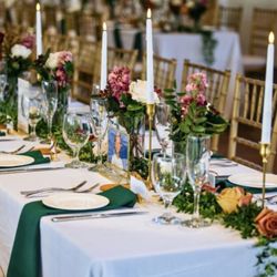 Posy’s Garden - Multiple vases between tapered candles atop greens and strewn blooms on long tables