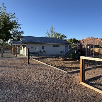 Sun Outdoors - An outdoor area at a pet-friendly resort in Moab, Utah, featuring a playground, a small building, and mountain scenery in the background. - Vacation Rentals Near Me - Moab, Utah