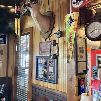 The Loose Caboose - A mounted deer head with antlers is displayed on a wooden-paneled wall in a restaurant decorated with vintage signs and memorabilia. - Barbeque Near Me - Spring, Texas