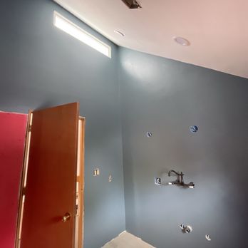 Unbreakable Remodeling - Bathroom renovation with angled ceilings - Room interior featuring blue painted walls, a partially open wooden door, and visible electrical outlets and fixtures, indicating ongoing renovation or construction work. - Drywall Installation & Repair Near Me - Beaverton , Oregon