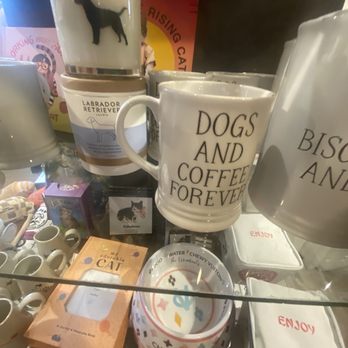 Art Effect - A collection of dog-themed mugs, candles, and accessories, including a mug with the phrase 'Dogs and Coffee Forever,' displayed in a gift shop setting. - Women's Clothing Near Me - Chicago, Illinois