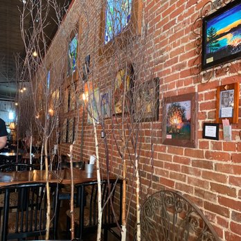 Lola - An American Bistro - a brick wall with a variety of framed pictures - Coffee & Tea Near Me - New Ulm, Minnesota