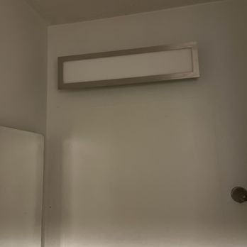 F&B Electric - New light installed. - A rectangular wall-mounted light fixture with a metallic frame is positioned near the ceiling on a white wall. - Electricians Near Me - Halethorpe, Maryland