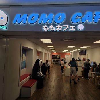 Momo Cafe - Momo Cafe's storefront displays a bright, illuminated sign with a cute character logo and Japanese text, leading into a cafe interior with customers. - Cafes Near Me - Schaumburg, Illinois