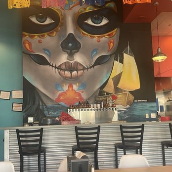 La Zenita - Fun mural - A mural features a sugar skull face with colorful decorative elements and a sailing ship in the background, inside a restaurant. - Mexican Near Me - Albuquerque, New Mexico