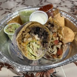 Chicken burrito with chips and sides of salsa verde, sour cream, guacamole and chili sauce. Chicken burrito with chips and sides of salsa verde, sour cream, guacamole and chili sauce.