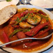 Photo of Kendall's Brasserie - Los Angeles, CA, United States. Cajun Shrimp Starter - Black Tiger Shrimp, Andouille Sausage, Peppers, Onions, Cajun Tomato Sauce, Lemon and Baguettes