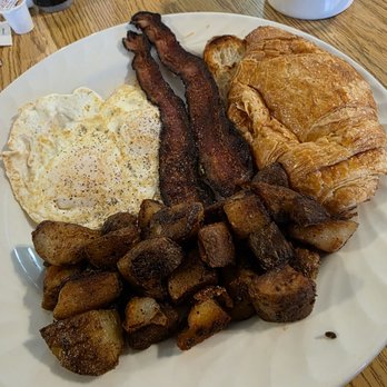 Vinton Cafe - Close-up of my Vinton Breakfast with fried eggs over easy, two bacon strips, potatoes, and a croissant. - Breakfast & Brunch Near Me - Vinton, Virginia Vinton Cafe - Close-up of my Vinton Breakfast with fried eggs over easy, two bacon strips, potatoes, and a croissant. - Breakfast & Brunch Near Me - Vinton, Virginia