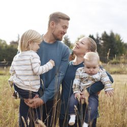 EGD Photography - A mother and father with their two children standing in a pasture at a family photo session