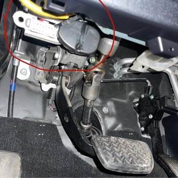 Pro Sound - The photo depicts the driver side footwell of a vehicle, showing the accelerator pedal, brake pedal, and various mechanical and electronic components, including wiring and connectors. - Car Stereo Installation Near Me - Newark, New Jersey