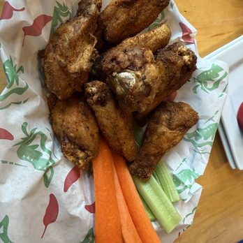 The Tipsy Trout - Cajun Dusted Wings - A basket of fried chicken wings accompanied by celery and carrot sticks, served on branded paper at a restaurant or pub. - American Near Me - Basalt, Colorado