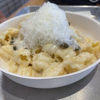 Tulipani - Creamy Lemon Tulipani - A bowl of pasta with a creamy white sauce, topped with shredded cheese and black pepper, served on a metal tray. - Pasta Shops Near Me - Albuquerque, New Mexico