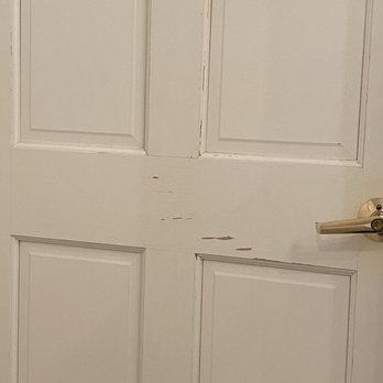 Delavan Lake Resort - A white wooden door with visible chipped paint and scratches, featuring a brass door handle on the right side. - Resorts Near Me - Delavan, Wisconsin