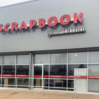 Scrapbook Generation - Scrapbook Generation. - The image shows the storefront of Scrapbook Generation, a craft store in Springfield, MO. The building has a modern exterior with large glass windows and a door in the center. The store's signage includes the name 'SCRAPBOOK' in large red letters with a black shadow, and the word 'generation' in smaller, gray letters. The windows display red and white decals with the store's name. A metal railing runs along the sidewalk in front of the store, and the reflection of trees and nearby buildings can be seen in the glass. The overall scene suggests a commercial retail location focused on scrapbooking supplies. - Arts & Crafts Near Me - Springfield, Missouri