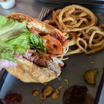 Twisted Root Burger - Classic burger minus one bite with onion straws and bacon cheese fries in the background - Burgers Near Me - Lubbock, Texas