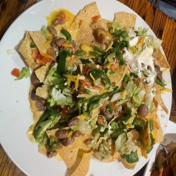 Alien Brew Pub - A plate of nachos with melted cheese, beans, chopped lettuce, jalapeños, and other toppings, served on a white dish. - Burgers Near Me - Albuquerque, New Mexico