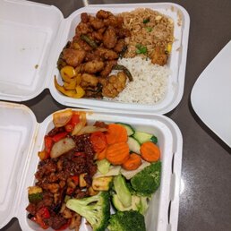 two takeout containers of food on a table two takeout containers of food on a table