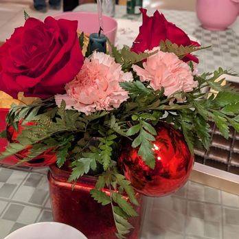 Ava Floret - Ugly arrangement, green candle, cheap plastic ornaments, pink carnations, and yellow bow.  I sent note to the shop, no response - Florists Near Me