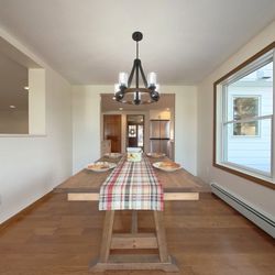 Stately Builders - Dining area with natural light, wooden table, and chandelier in a cozy kitchen setup.