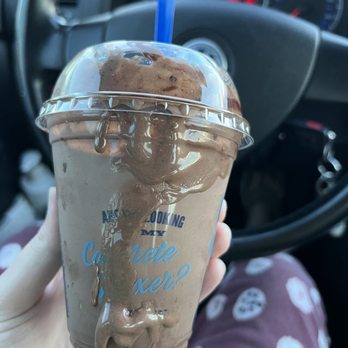 Culver's - Handed to me like this in the drive-thru. - A chocolate frappuccino with a blue straw is spilling over the sides, held by a person inside a vehicle. - Burgers Near Me - Westminster, Colorado