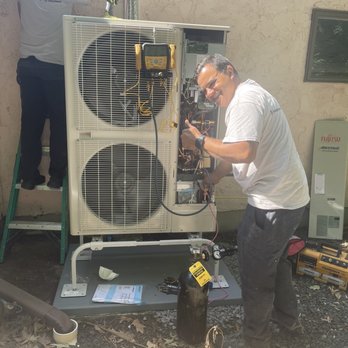 SumZero Energy Systems - It's alive :) - Two technicians work on an outdoor HVAC system, with one on a ladder and the other using tools to service the unit. - Heating & Air Conditioning/HVAC Near Me - Holliston, Massachusetts