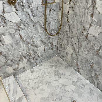 AR Remodeling Group - a marble shower - A shower area with marble tiles on the walls and hexagonal marble tiles on the floor, featuring gold fixtures and a drain. - General Contractors Near Me - Chicago , Illinois