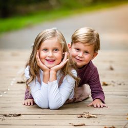 Novitsky Photography - Brother and sister side by side, their laughter and bond evident, capturing the timeless connection and joy of siblinghood in a single frame