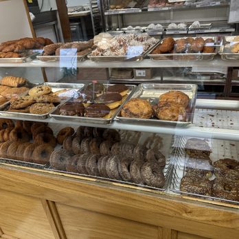 Dixie Donuts - a variety of baked goods - A bakery display case contains an assortment of donuts, cookies, and pastries, with some items topped with chocolate, powdered sugar, or icing. - Donuts Near Me - Norwich, Connecticut