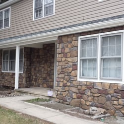 Front of house; siding, stone facade, roofing, gutters.