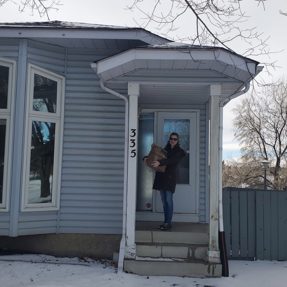 CalgaryListings Group - Chantelle took this photo of me in front of my new home. That hefty basket in my arms is stuffed with handpicked housewarming gifts! - Real Estate Agents Near Me - Calgary, Alberta