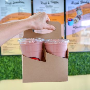 Groovy Smoothie - a hand holding two cups of smoothie - Juice Bars & Smoothies Near Me - Arcadia, Florida