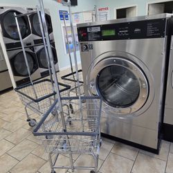 Laundry carts next to one of the large washing machines.
