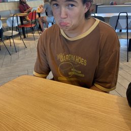 a young man sitting at a table with a donut in his mouth