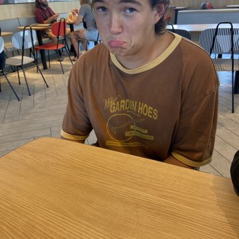 McDonald's - a young man sitting at a table with a donut in his mouth - Fast Food Near Me - Fort Morgan, Colorado