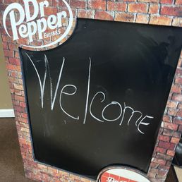 a welcome sign in front of a brick wall