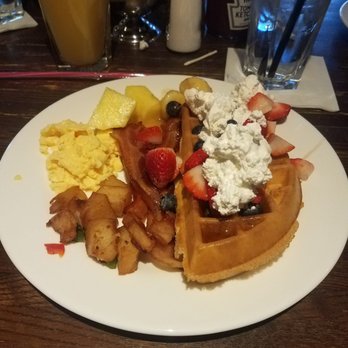 KC Prime - Half a waffle with with ayrup, blueberries, strawberries and whipped cream.  Scrambled eggs, breakfast potatos and bacon. - Steakhouses Near Me - Lawrenceville, New Jersey