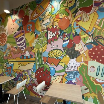 Jamba - A vibrant, cartoon-style mural featuring fruits, vegetables, and food-related graphics decorates a wall in a casual dining space. - Juice Bars & Smoothies Near Me - Albuquerque, New Mexico