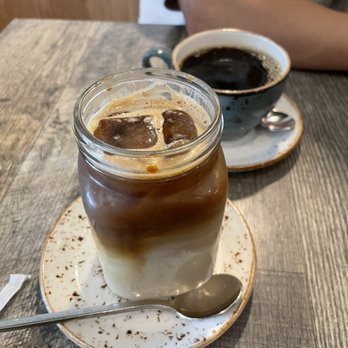 The Aussie Grind - Top to bottom: Mug of House Brew Coffee and 16 oz. Iced Vanilla Soy Latte - Cafes Near Me - Frisco, Texas The Aussie Grind - Top to bottom: Mug of House Brew Coffee and 16 oz. Iced Vanilla Soy Latte - Cafes Near Me - Frisco, Texas