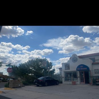 Casa Talavera - Entrance with street view - Street view showing a building with a sign for Rio Grande, a parked black car, and a blue sky with clouds. - Home & Garden Near Me - Albuquerque, New Mexico