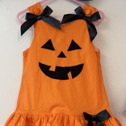 Bonnets & Buttons - Romper dress all ready for Halloween. A happy pumpkin with bows and buttons on each shoulder and a bow on the bottom left side.