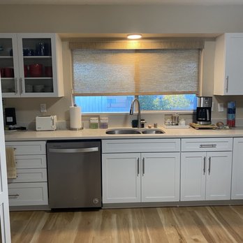 Strahle Tile & Granite - Kitchen remodel w Quartz top - A kitchen features white cabinetry, a window with a beige roller shade, and appliances including a coffee maker and toaster on the countertop. - Flooring Near Me - Albuquerque, New Mexico