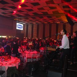 S4 Entertainment - A musician performs on stage, bathed in red light, while a full banquet hall watches