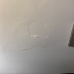 Next to the bed light switch is a damaged wall