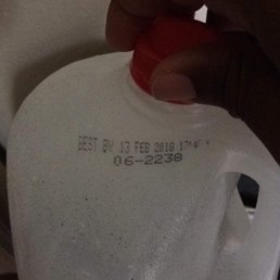 a hand holding a gallon of milk