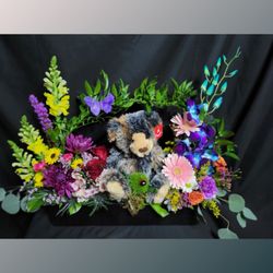 Brindle bear in a box of flowers.
